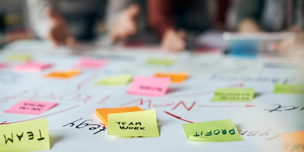Team brainstorming session with colorful sticky notes labeled team work and profit on a table